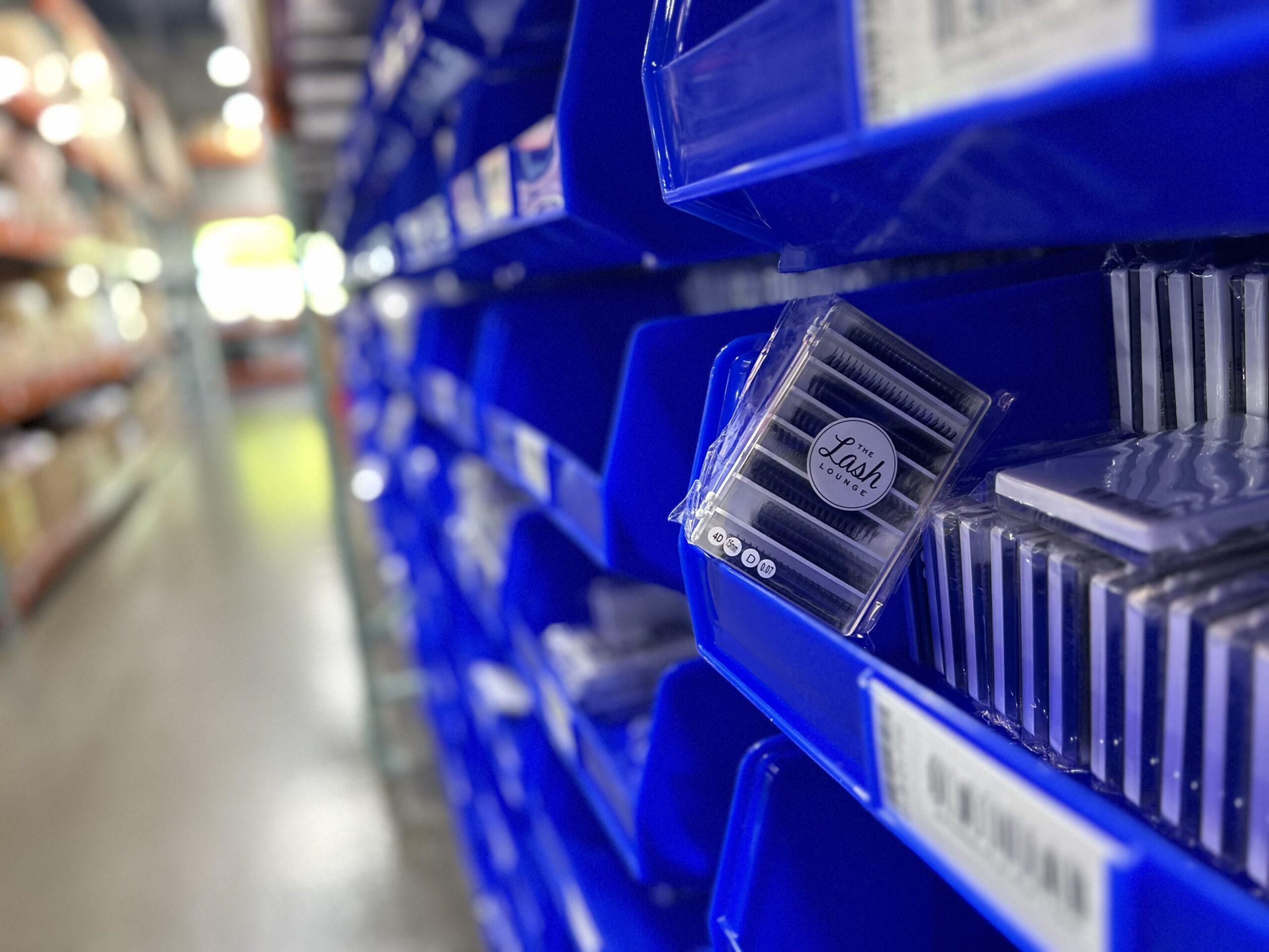 The Lash Lounge franchise's eyelash products stacked in blue bins in a warehouse.