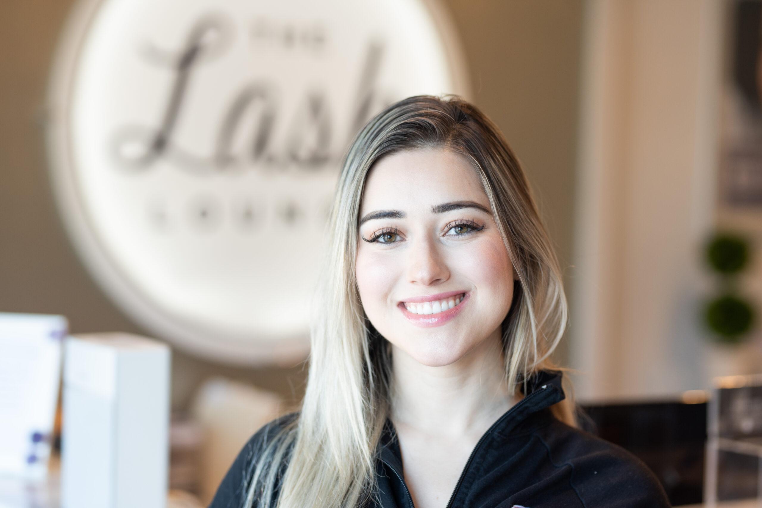 A Lash Lounge franchise stylist smiling in a black quarter zip.